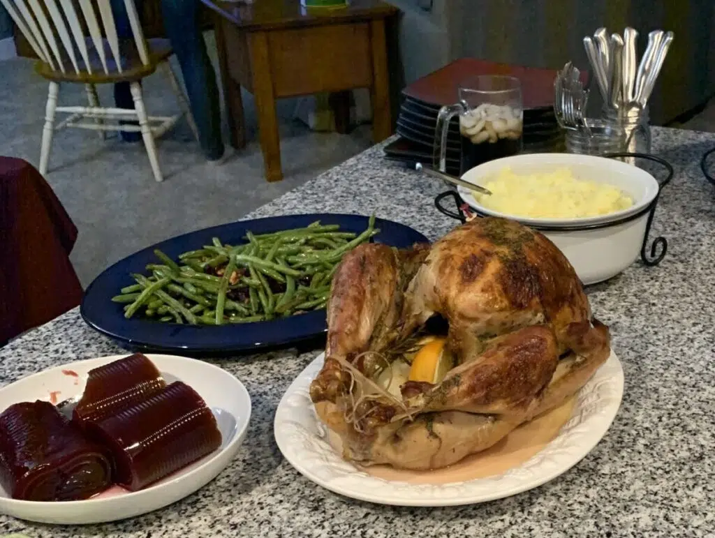 A Thanksgiving feast including roasted green beans, cranberry sauce, mashed potatoes, and a Kamado Joe Smoked Turkey.