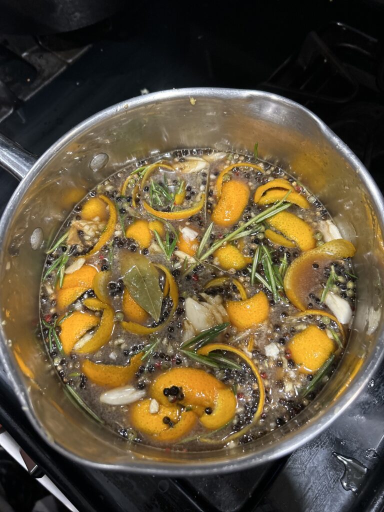 A pan filled with brine including orange peels, bay leaves, garlic, onions and rosemary for making a smoked turrkey.