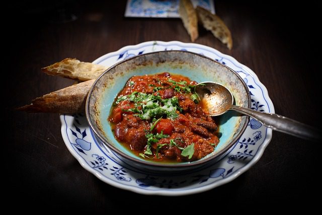 A bowl of chili with a side dish of crusty bread for dipping.