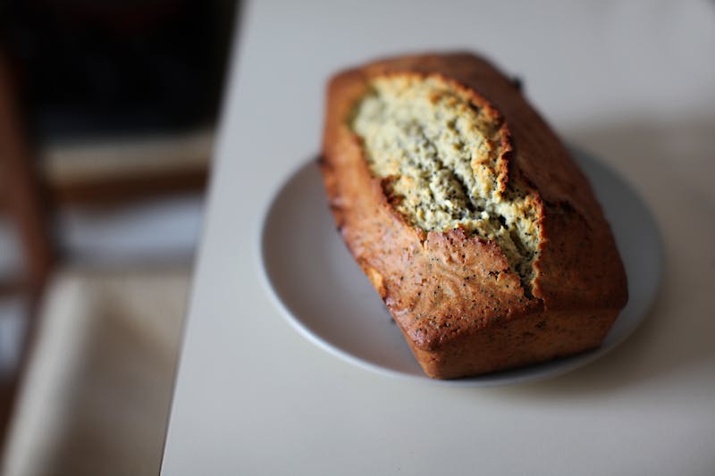 A loaf of freshly baked banana bread without butter on a white plate on the counter.