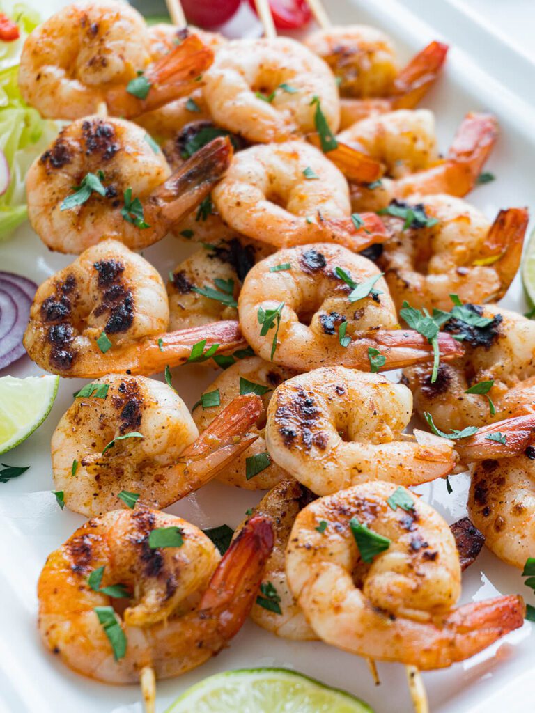Chipotle Lime Shrimp Kabobs with fresh parsley for a garnish on a white plate.