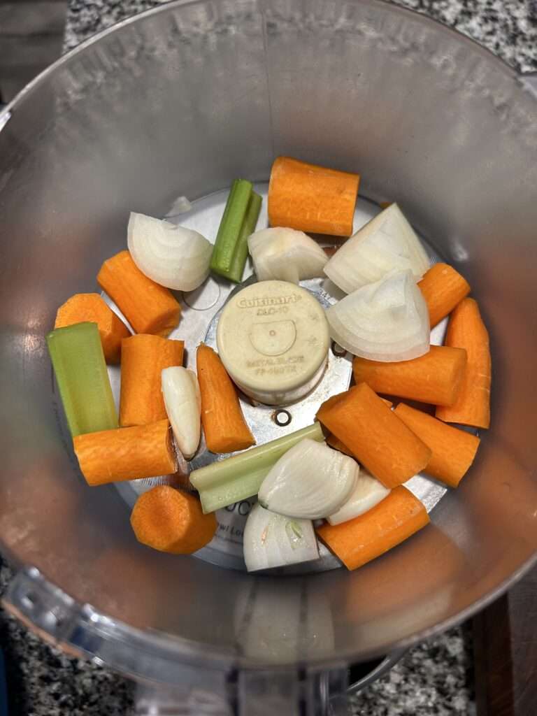 Roughly chopped carrots, onions, garlic cloves and celery in a food processor for Homemade Bolognese Sauce.