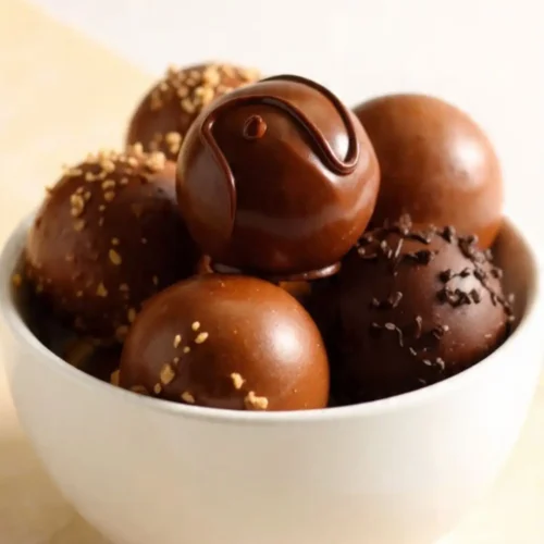Assorted chocolate truffles in a white bowl, nuts and sprinkles