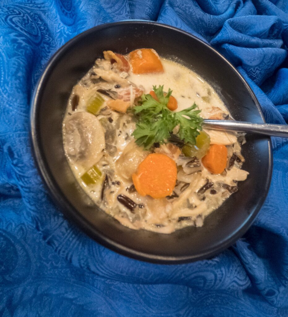 Creamy Chicken and Wild Rice Soup in a black bowl on a blue napkin.