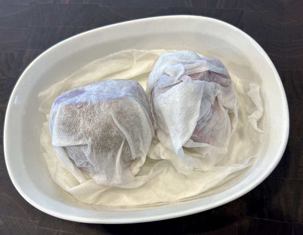 Beet roots wrapped in dampened paper towels in a corning wear dish to microwave them.