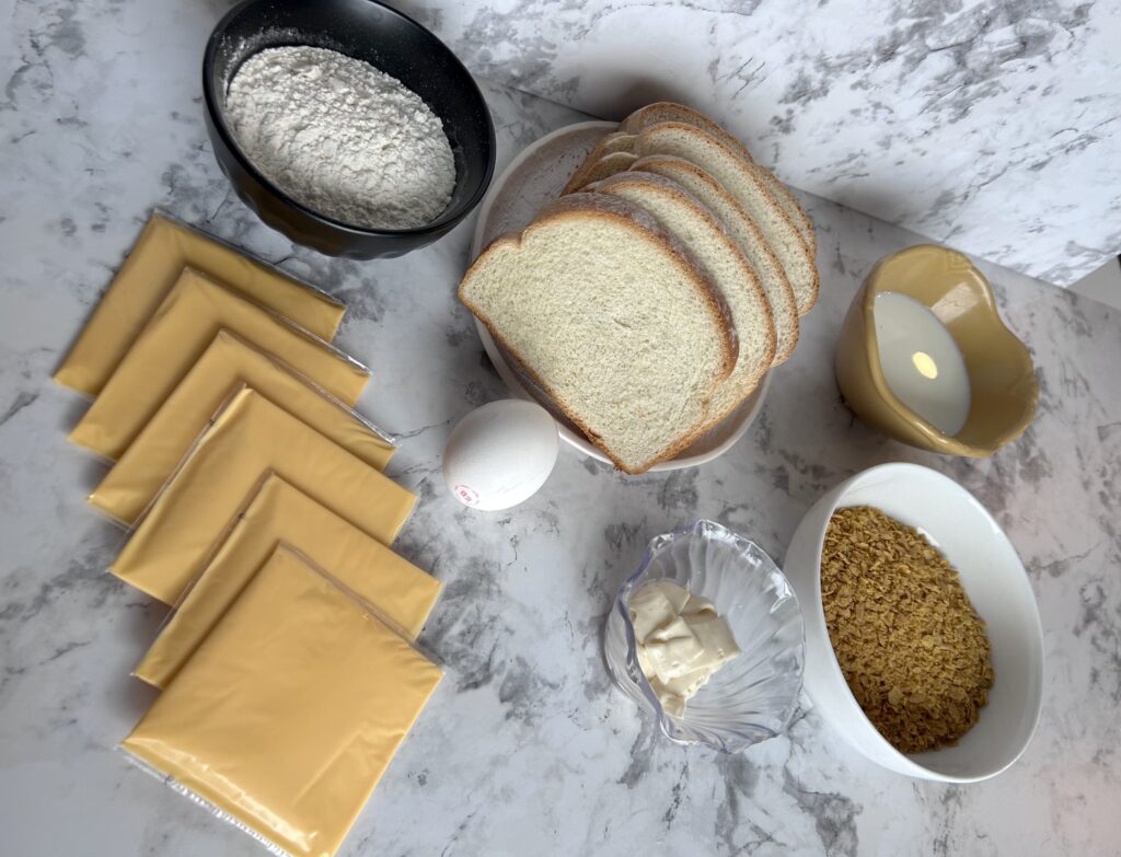 The ingredients for a Nebraska Cheese Frenchee including milk, eggs, cheese, bread, flour, and corn flakes.