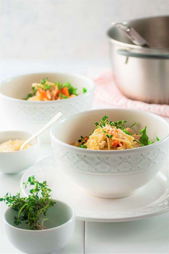 Two bowls of chicken fideo soup with a large stock pot of soup in the background.