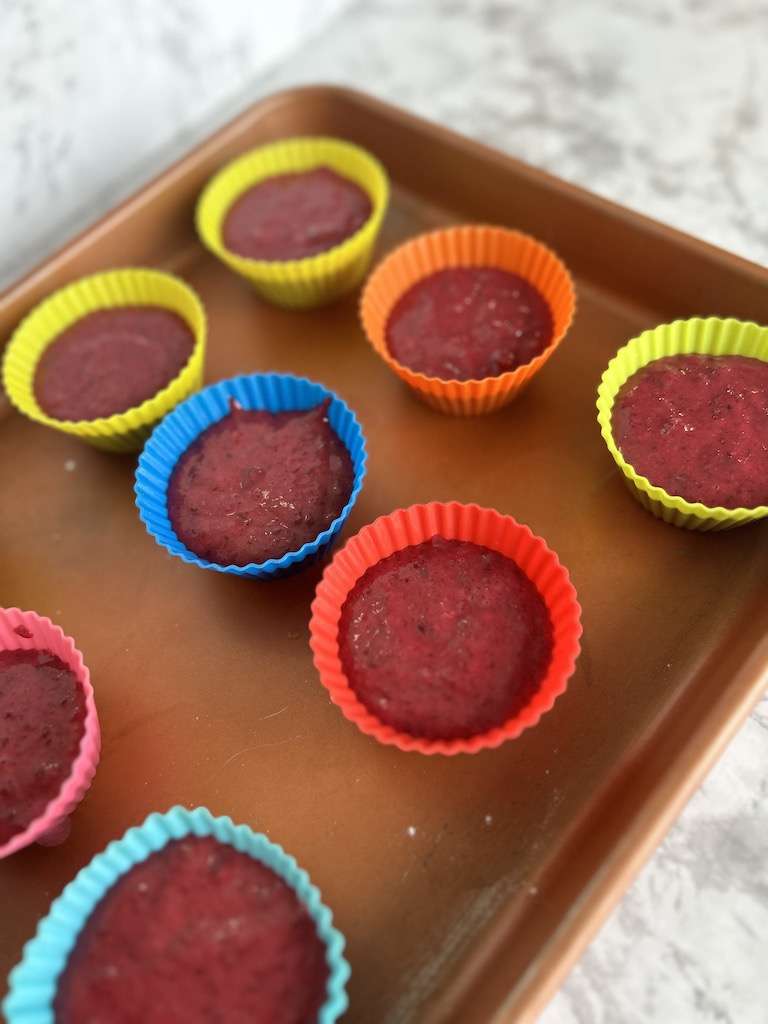 Beet chocolate muffin batter in silicon baking cups on a baking sheet.