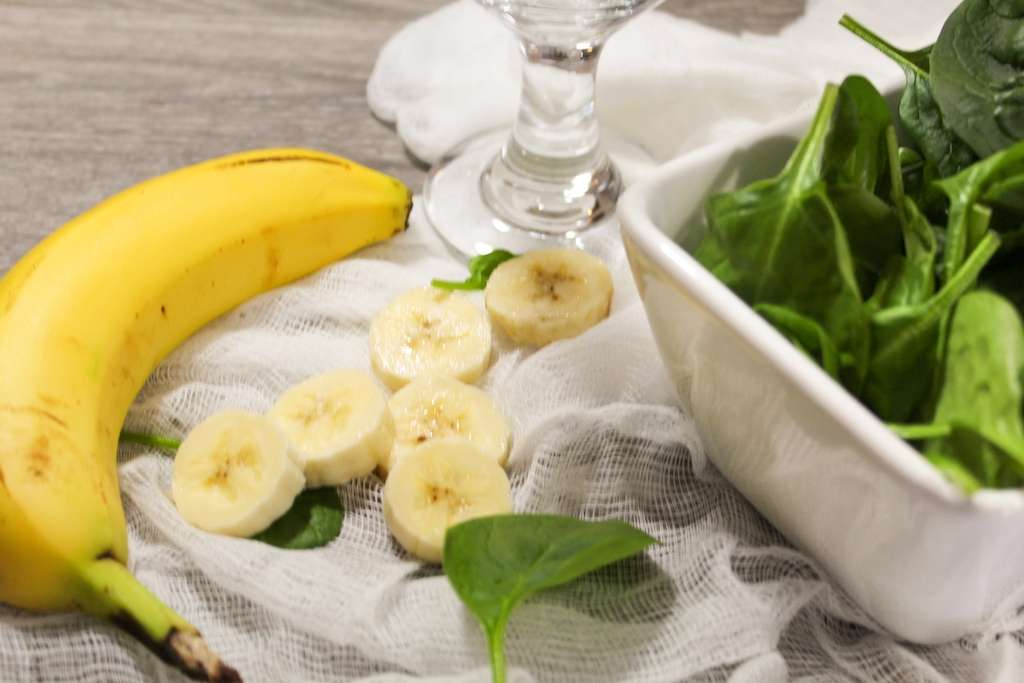 Banana and spinach smoothie ingredients including fresh bananas and fresh spinach leaves.