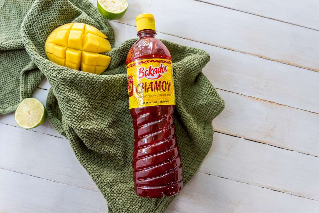 Bottle of chamoy sauce with green napkin, mango and limes