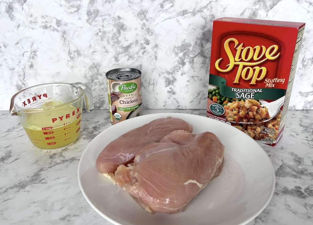 The 4 ingredients needed for easy slow cooker chicken and stuffing including boneless chicken breasts, chicken broth, a can of cream of chicken soup and a box of stuffing.