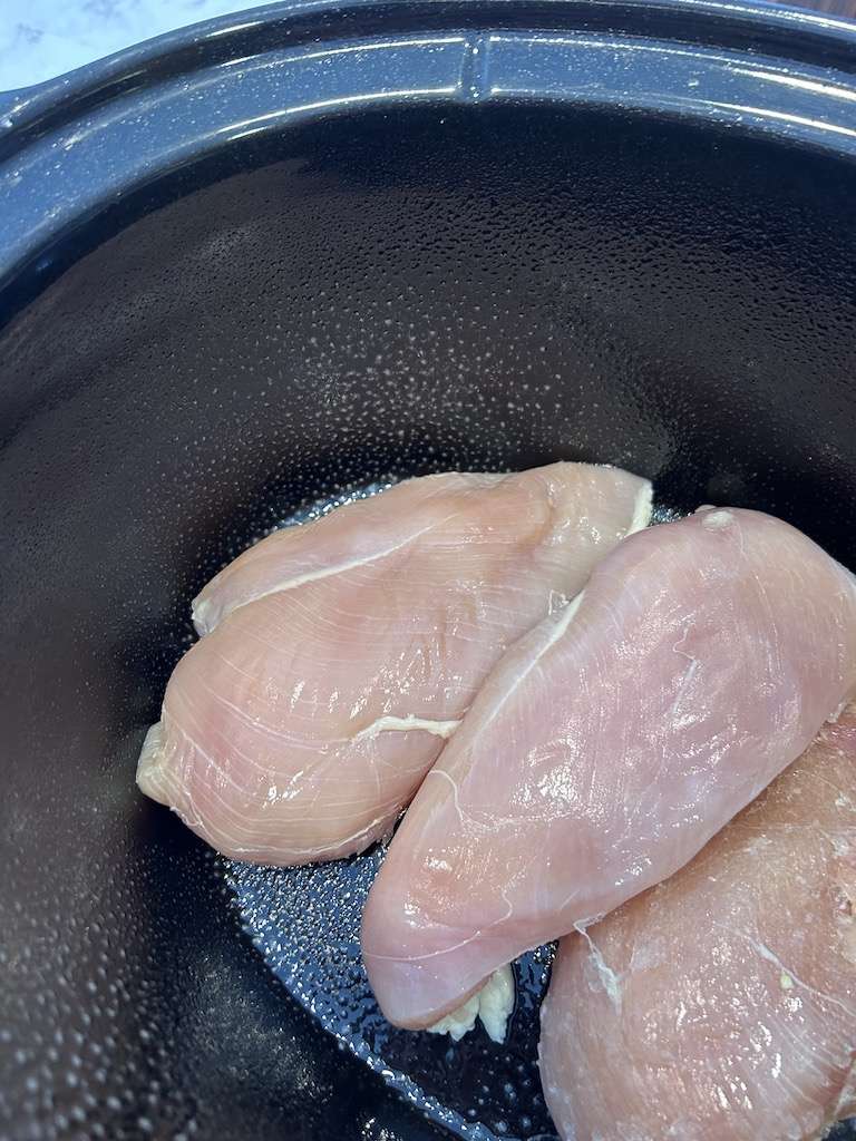 Boneless chicken breasts in a crock pot sprayed with non-stick cooking spray.