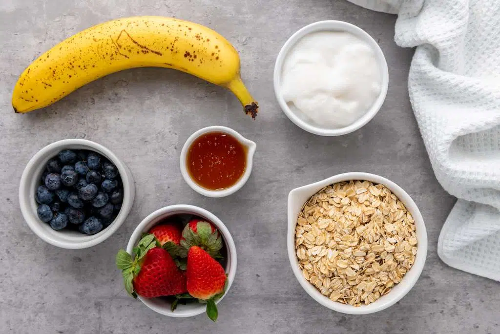 Granola Berry Cups - A Delicious Treat Granola Berry Cups Ingredients including rolled oats, bananas, yogurt, fresh blueberries, fresh strawberries and raw honey.