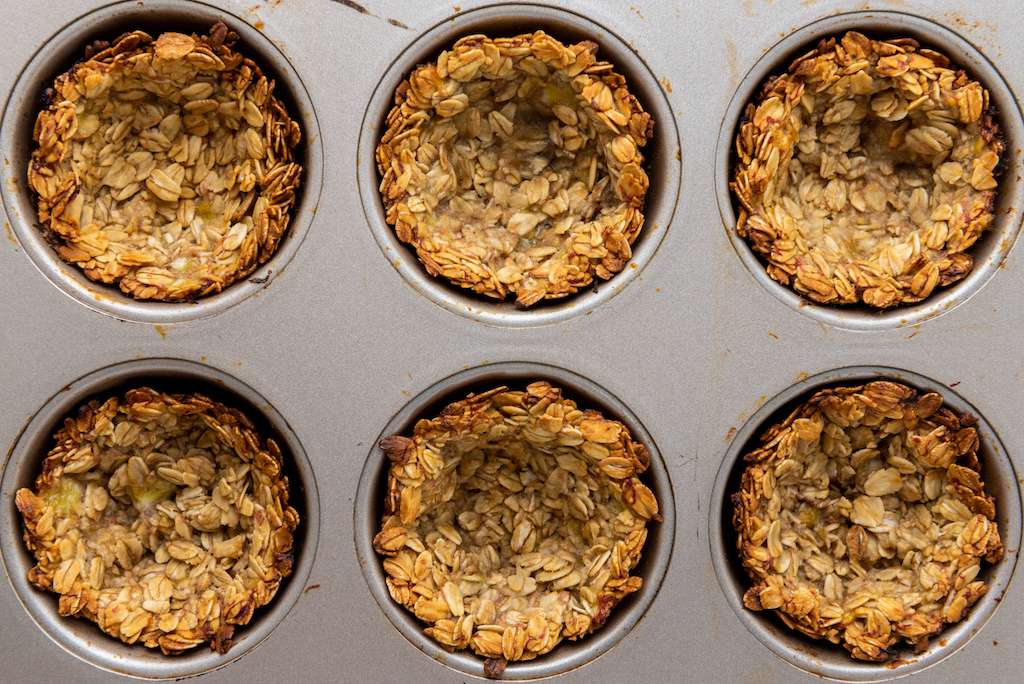 Baked mini granola cups in a muffin tin.
