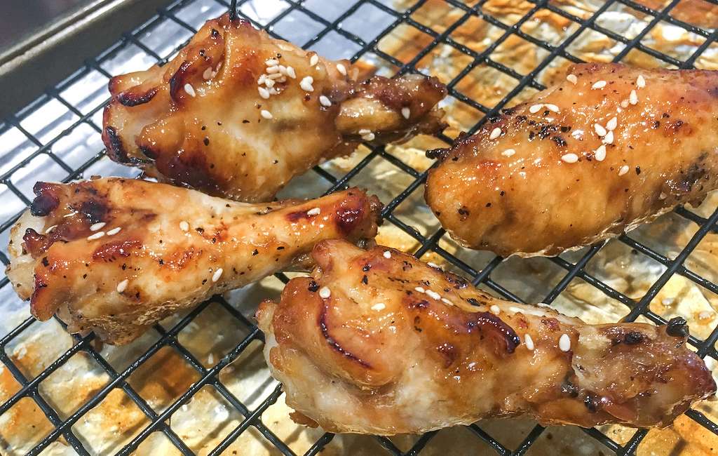 Honey garlic chicken wings on a baking pan for broiling.