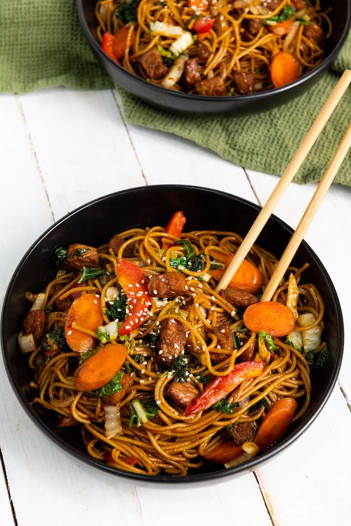 Instant Pot Pork Lo Mein on a black plate with wooden chopsticks