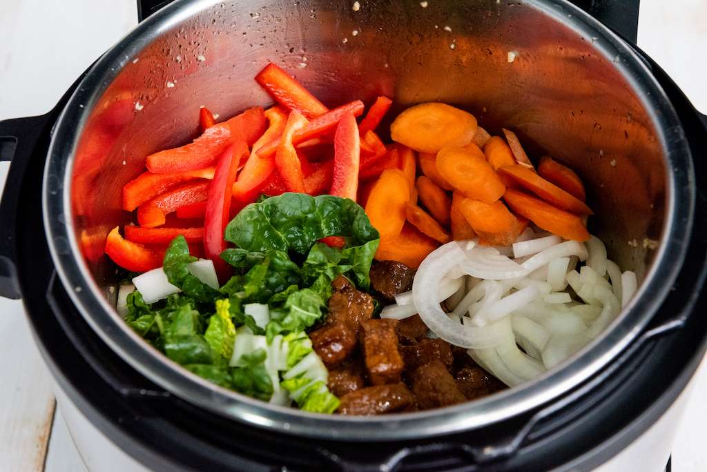 Adding the veggies into the instant pot for instant pot pork lo mein