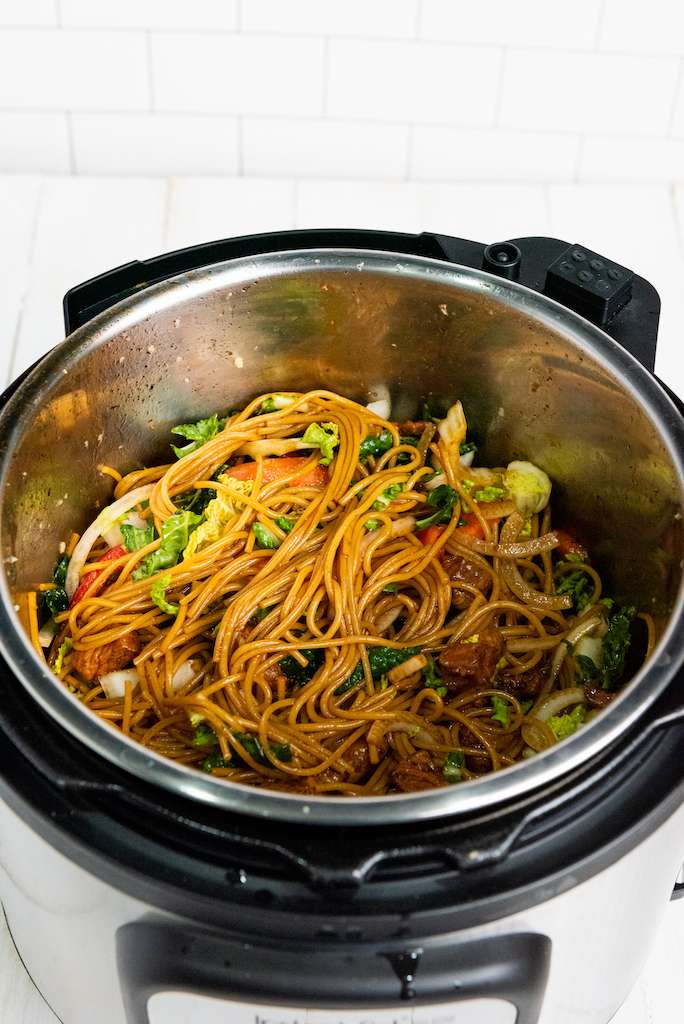 Mixing the veggies and noddles together for instant pot pork lo mein