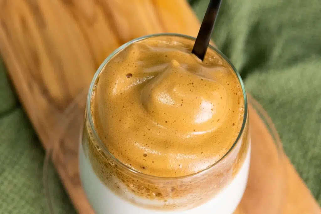 Looking down at a glass of Dalgona latte topped with whipped coffee foam.