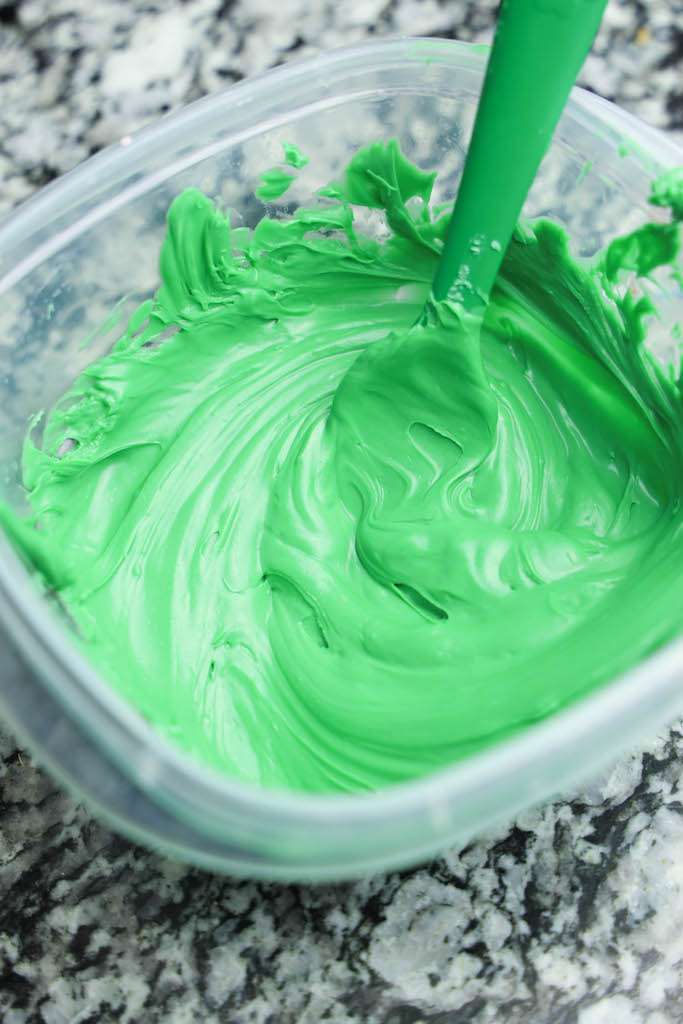 A tuperware full of melted green candies with a spoon.