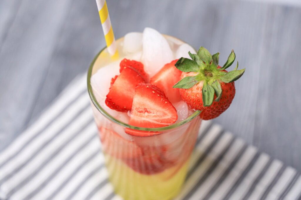 Strawberry limoncello lemonade in a tall glass garnished with a fresh strawberry and a straw.