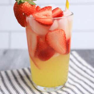 Side view of limoncello strawberry lemonade on a gray and white stripped napkin with straw