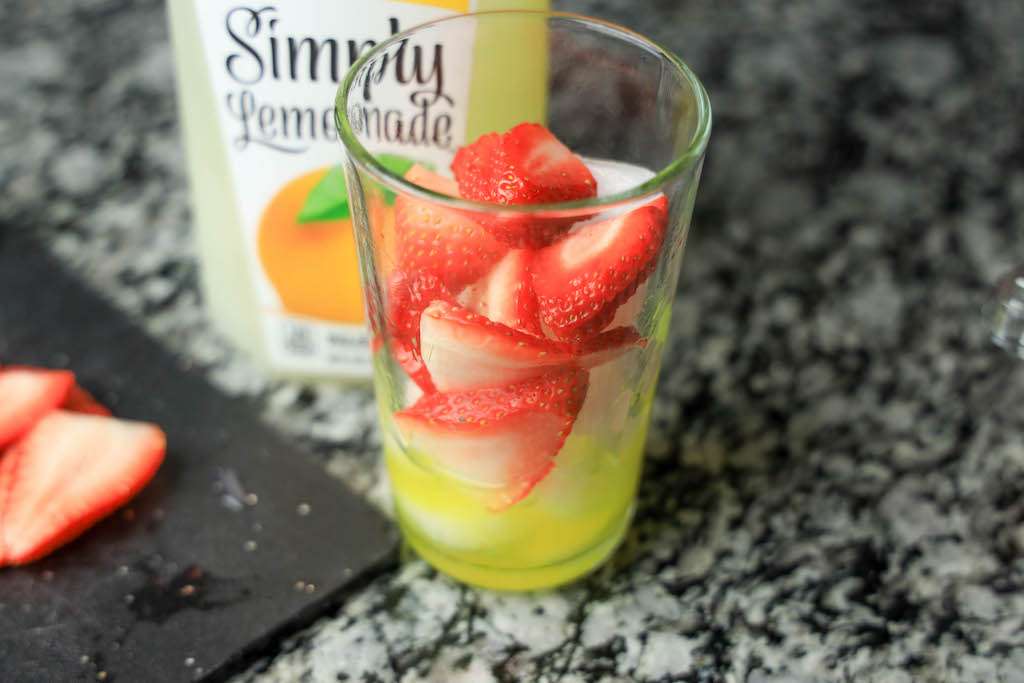 Fresh sliced strawberries in a tall glass with lemonade.