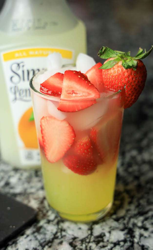 A tall glass of strawberry limoncello lemonade garnished with a fresh strawberry.