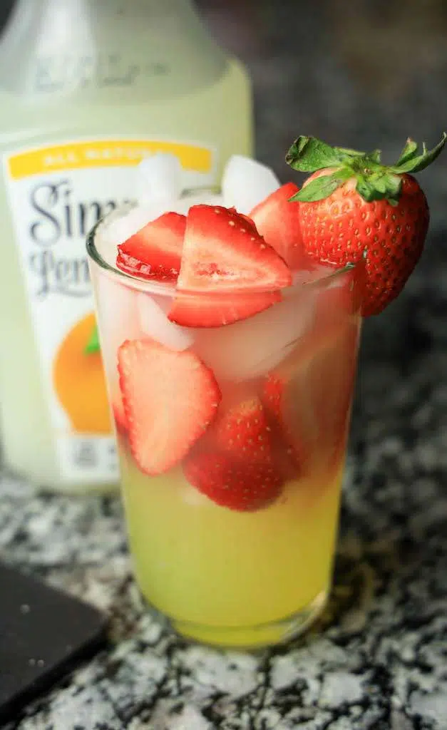 A tall glass of strawberry limoncello lemonade garnished with a fresh strawberry.