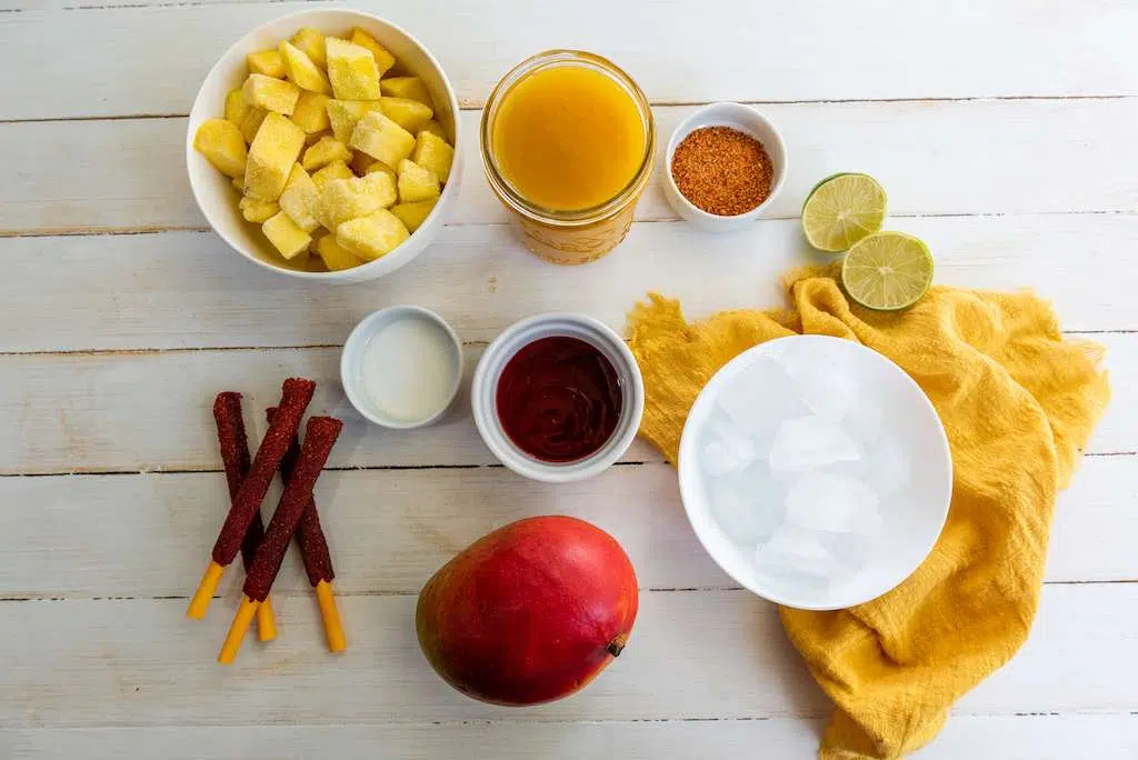 Mangonada Chamoyada Ingredients in small bowls on a wooden background.