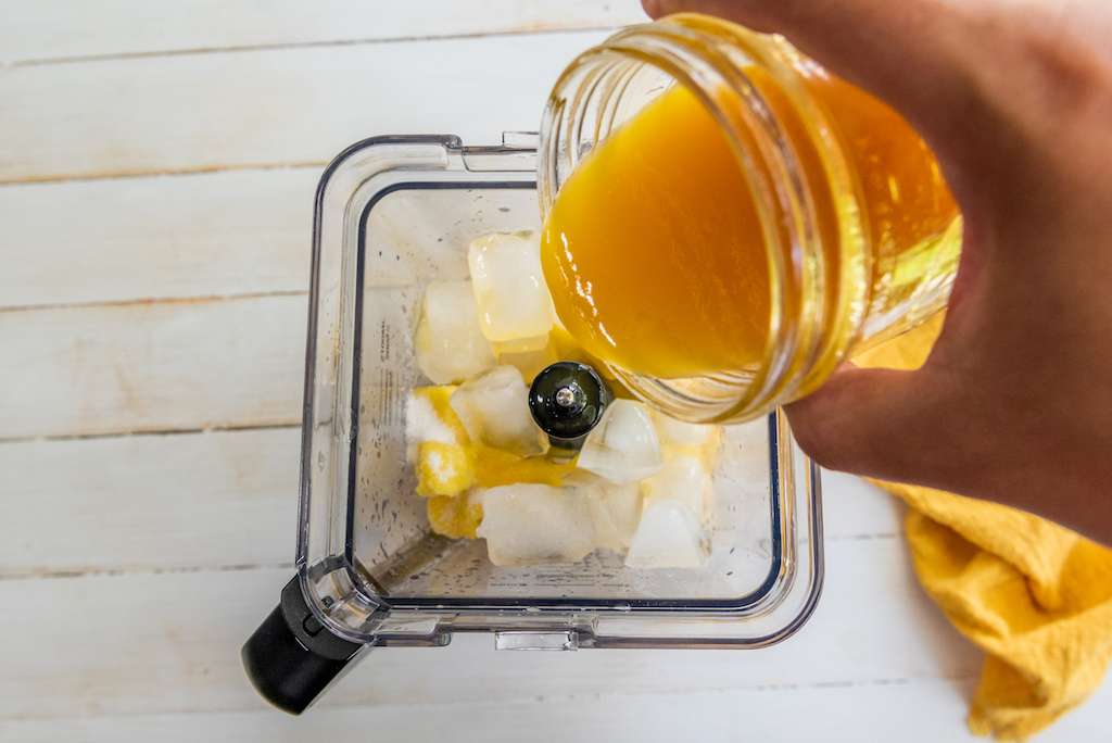 Pouring the mango nectar into the blender with ice.