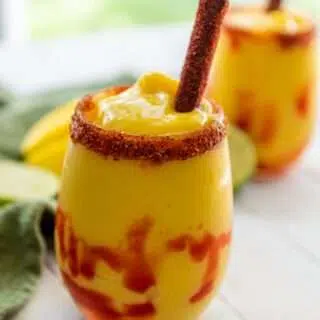 Close up of mangonada in a glass with a tamarind straw