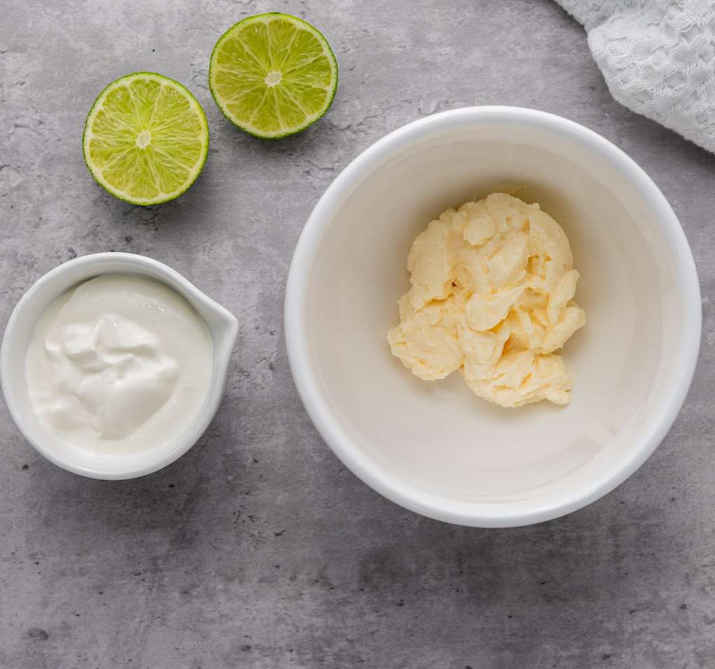 Mayonnaise, Mexican crema and a halved fresh lime to be mixed together to make the elote sauce.