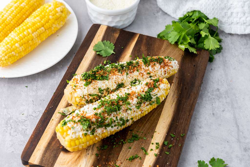 Mexican Street corn on a wooden cutting board.