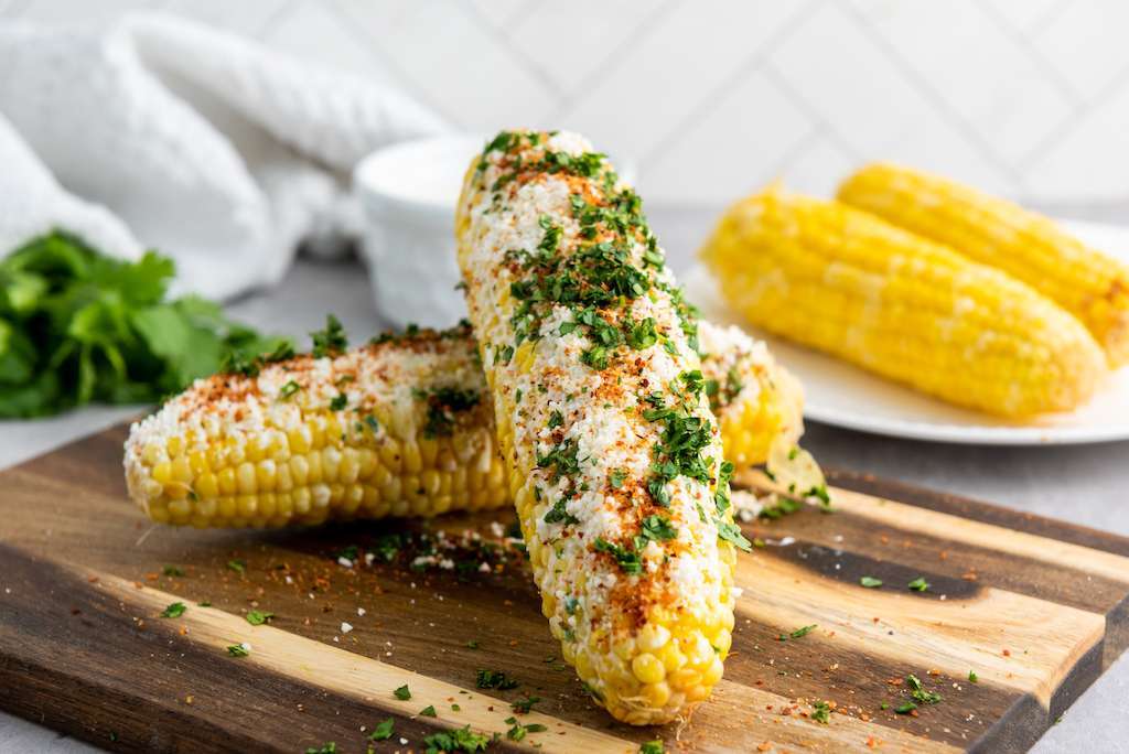 Finished Mexican street corn with cotija, cilantro, and Tajín.