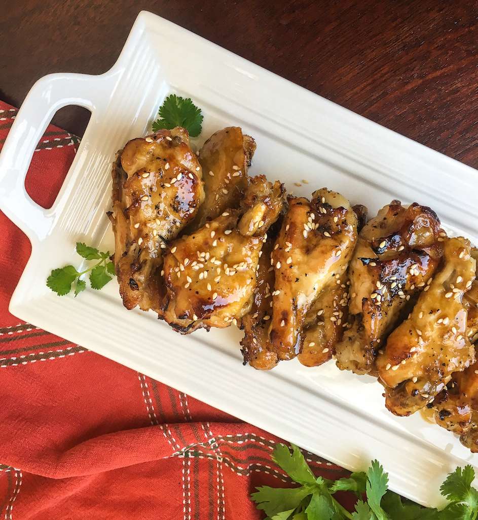 Sesame Honey Garlic Chicken Wings on a platter with  a garnish of fresh parsley and sesame seeds.