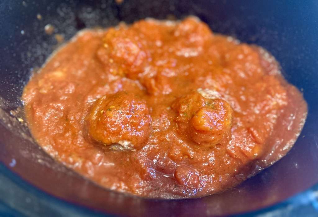 Stuffed meatballs covered with marinara sauce in a slow cooker.