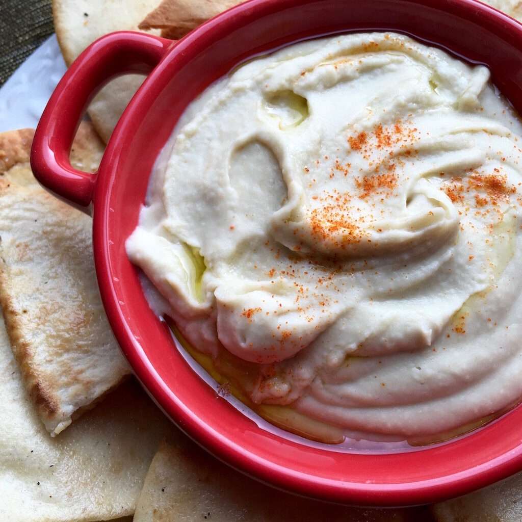 White Bean Dip with Seasoned Pita Chips and drizzled with olive oil.