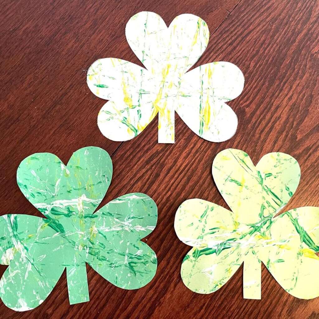 Three marbled shamrock paper crafts for St. Patrick's Day on wood