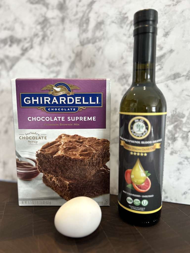 A box of Ghirardelli chocolate supreme brownie mix, an egg and a bottle of blood orange olive oil to make easy blood orange brownies.