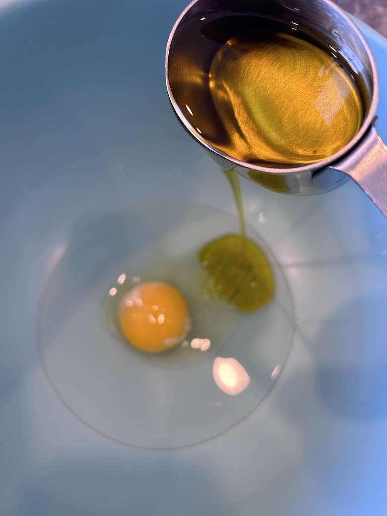 Mixing the blood orange olive oil and egg in a blue mixing bowl.