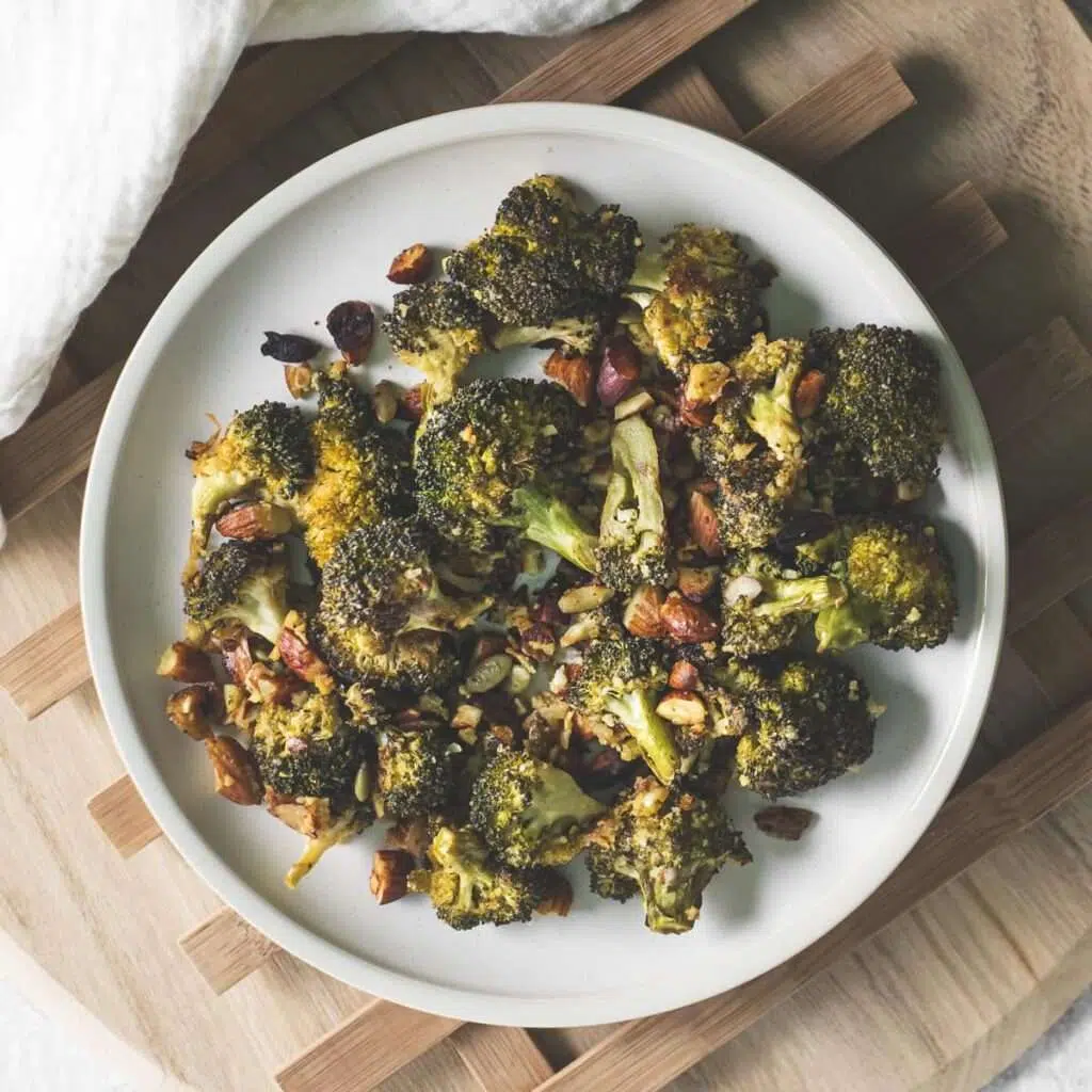 Oven-roasted broccoli with chopped almonds on a white plate