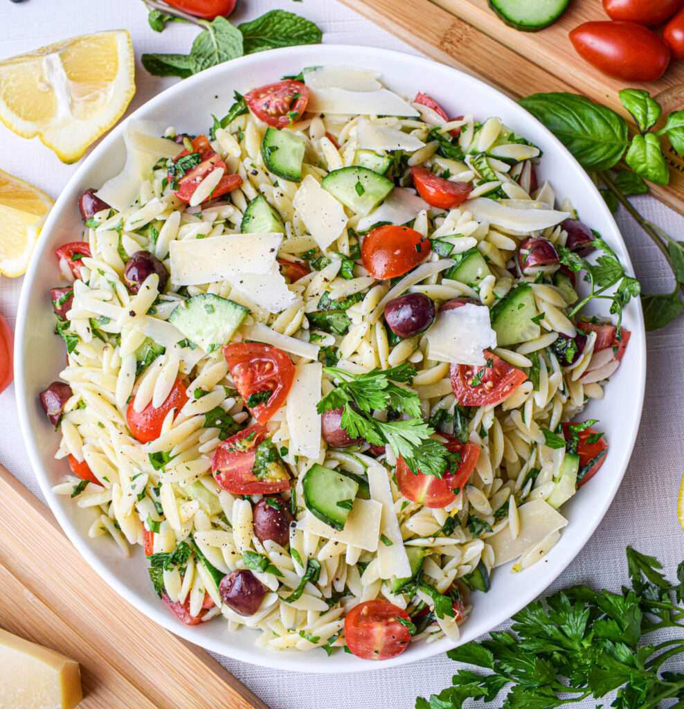 Mediterranean orzo pasta salad with tomatoes, cucumber, olives, and parmesan