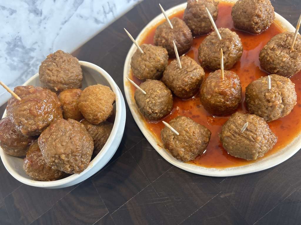 Drunken chili meatballs on a plate filled with sauce.