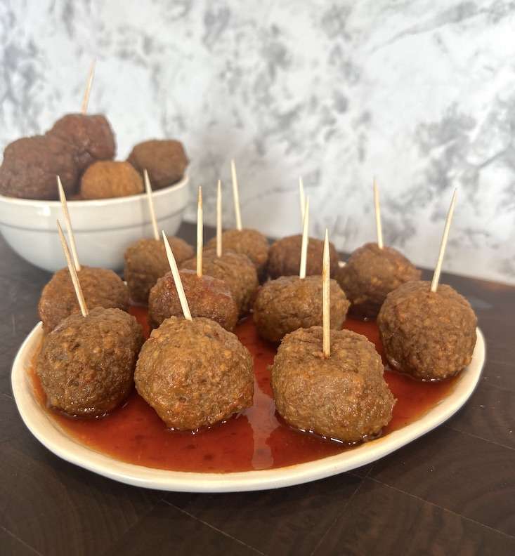 A plateful of drunken meatballs with beer with toothpicks for serving.