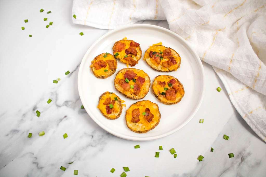 Air fryer loaded potato slices on a white plate garnished with chopped chives.