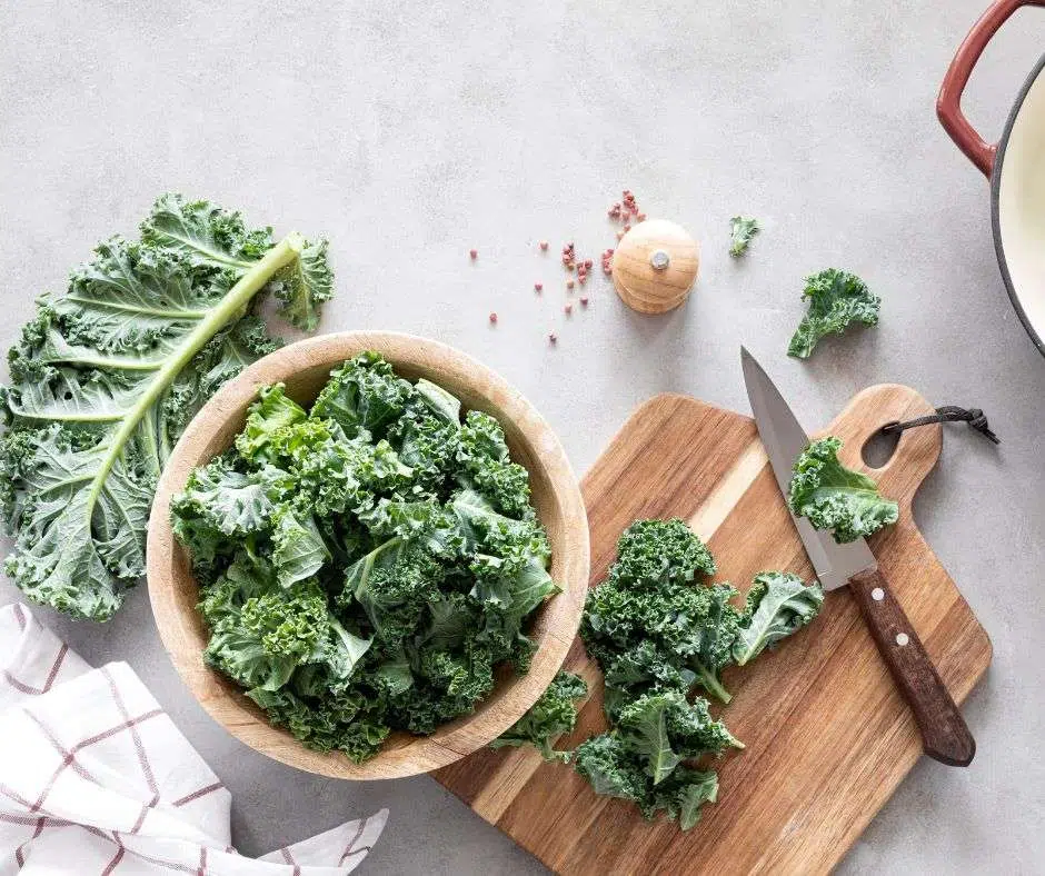 Fresh kale chopped on a cutting board with a knife.