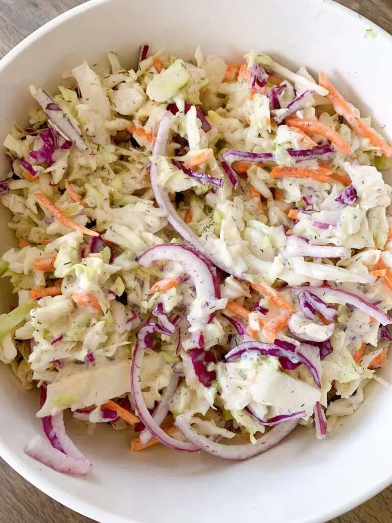 Creamy coleslaw with cabbage, carrots, and red onion in bowl