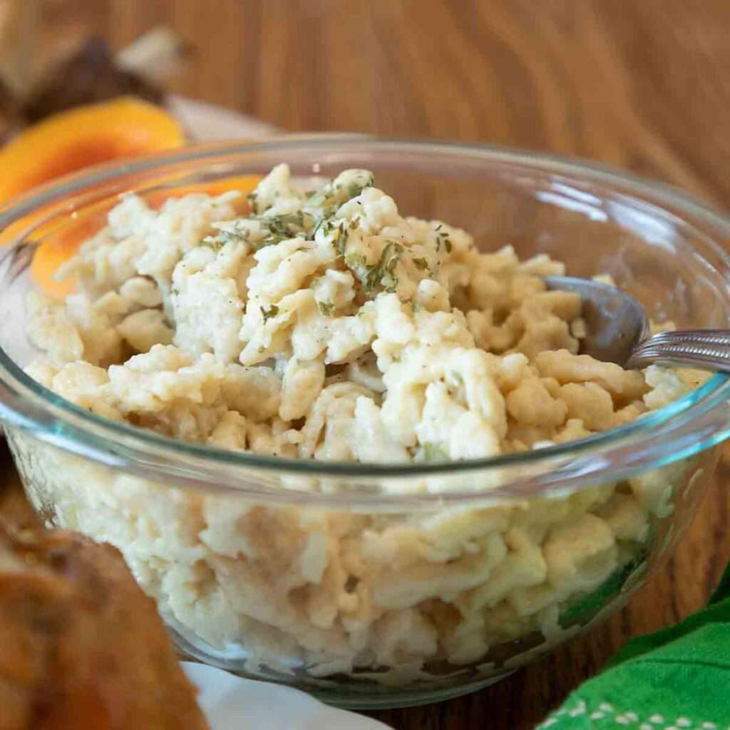Creamy German spaetzle egg noodles in a glass bowl with herbs