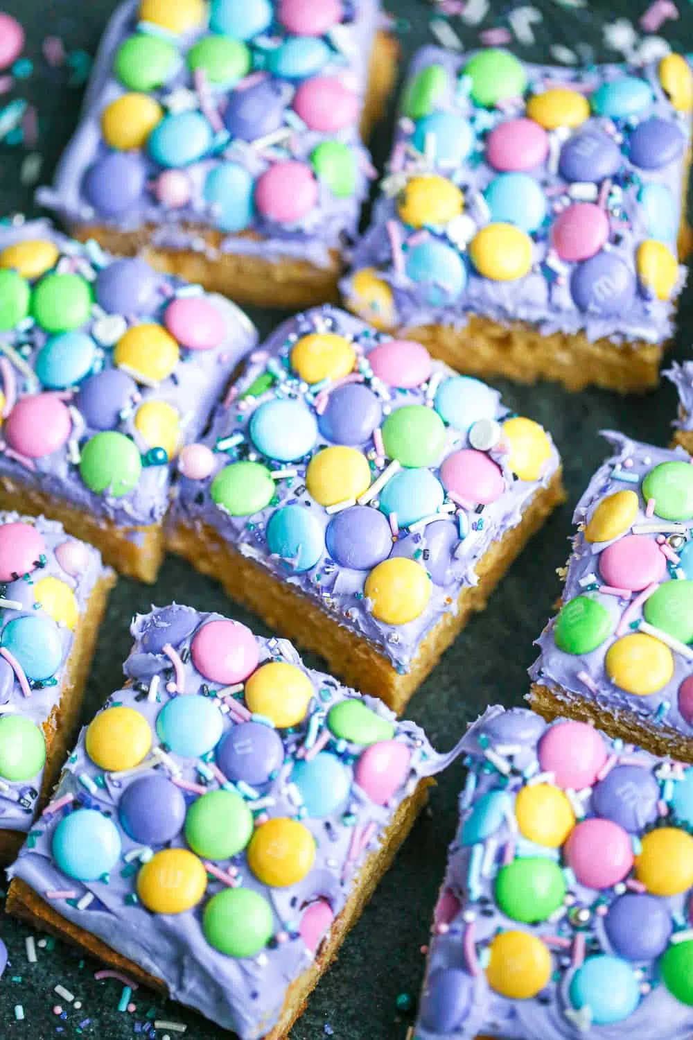 Sugar cookie bars with purple frosting, pastel M&M candies, and sprinkles